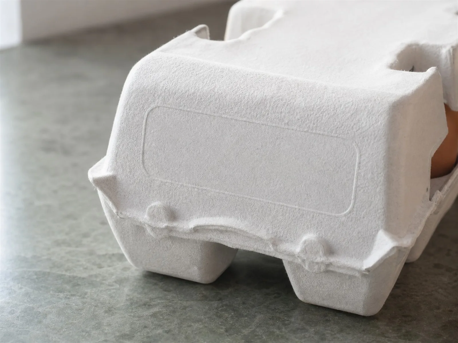 Close-up of a white egg carton lid where the pack date and plant code are stamped